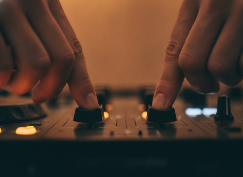 Two hands working separate channels on a single mixer